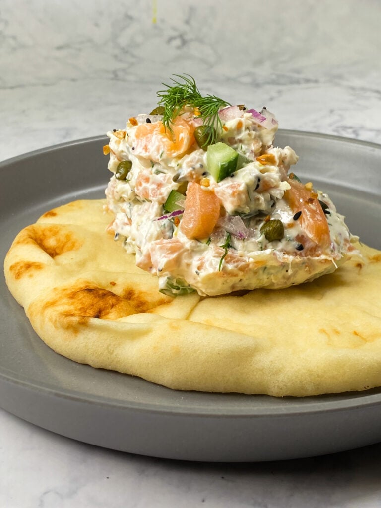 Smoked salmon lox dip with cucumber, capers and fresh dill spread on naan