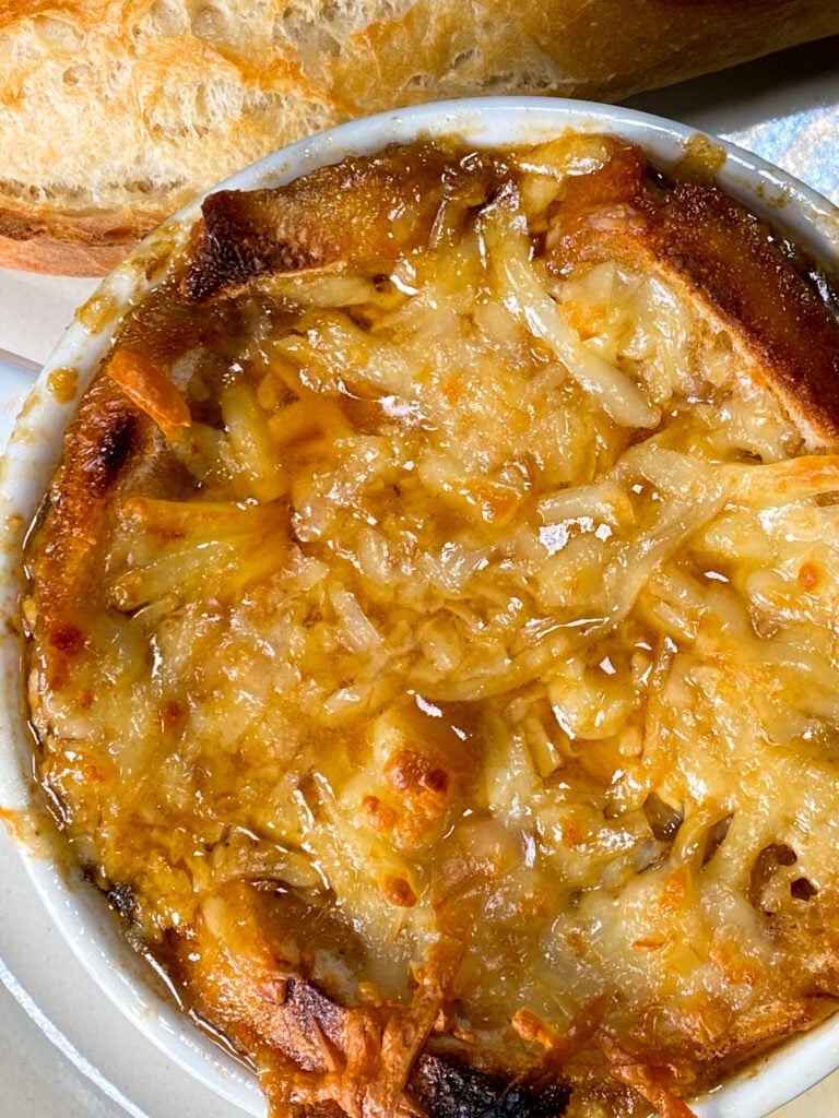 philly cheesesteak french onion soup topped with toasted bread and melted cheese