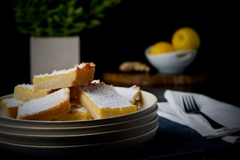 Honey lemon and ginger bars dusted with powdered sugar on small plates