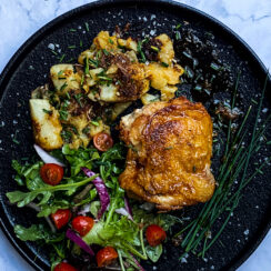 crispy nashville style hot chicken on a black plate with a garden salad