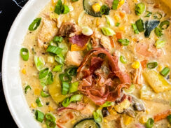 summer veggies and chicken chowder in a bowl topped with prosciutto