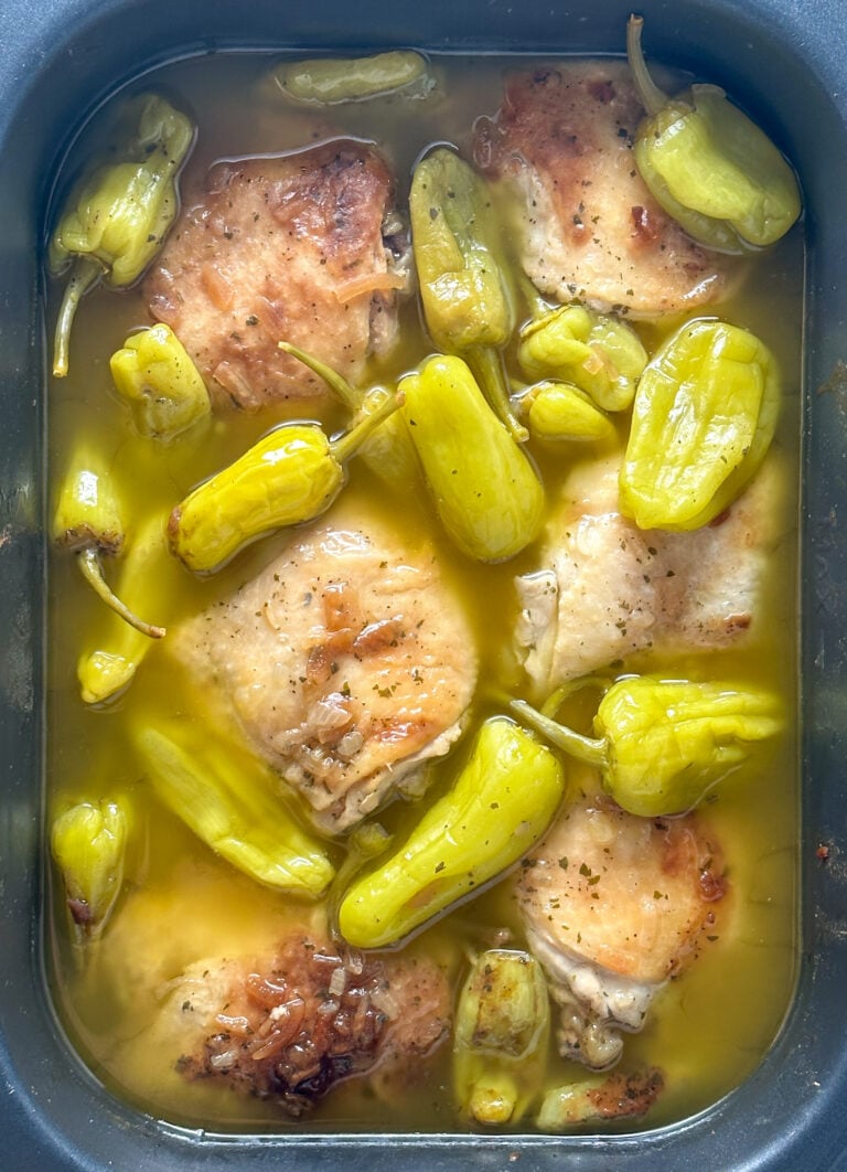 slow cooker mississippi chicken thighs with pepperoncini peppers in a gray crockpot