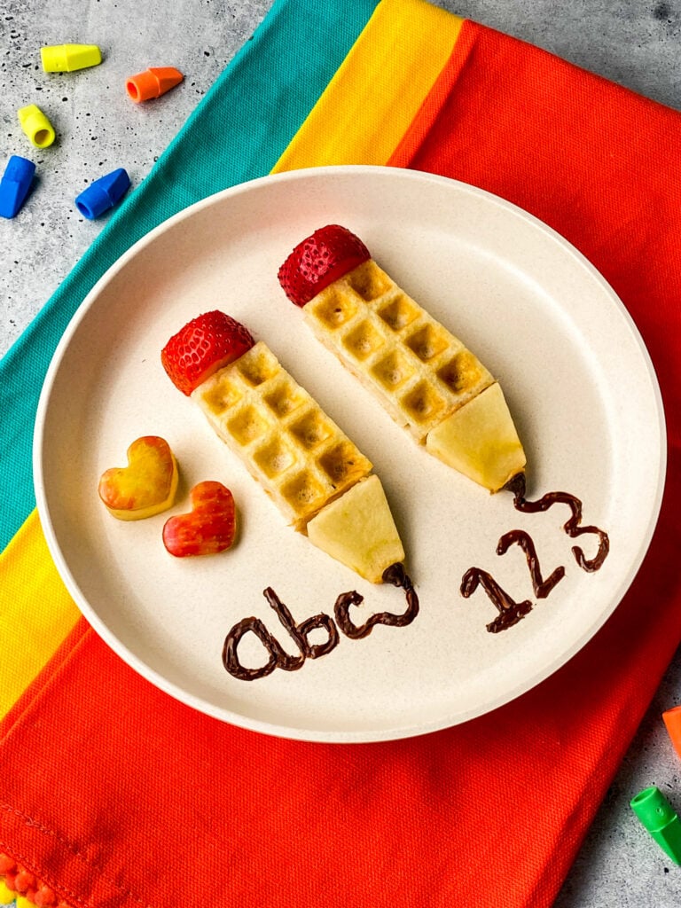 waffles cut and decorated to look like school pencils with strawberry and apple slices