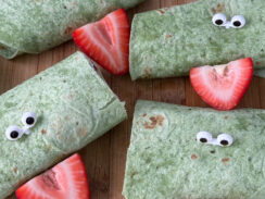 spinach tortilla rolls with eye tooth picks and strawberry to look like a frog
