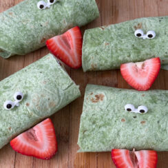 spinach tortilla rolls with eye tooth picks and strawberry to look like a frog