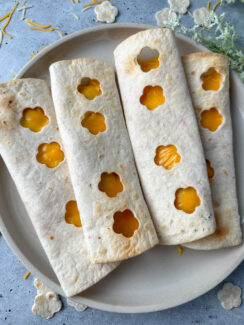 crispy air fryer cheese tortilla wraps with flower cut-outs down the middle on a white plate