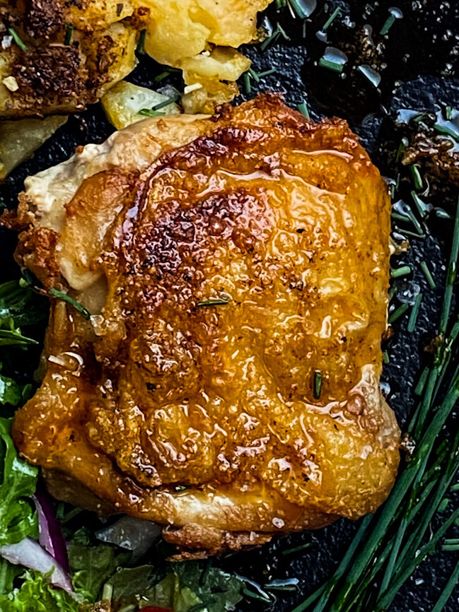 crispy nashville style hot chicken on a black plate with a garden salad