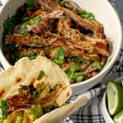 an almond flour tortilla filled with shredded crockpot carnitas meat served with lime wedges