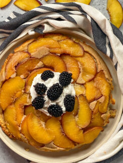 Peach upside down cake made with almond flour and topped with whipped cream and black berries