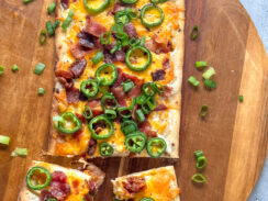 flatbread pizza with cream cheese, melted cheddar cheese, crispy bacon, jalapeño slices, and green onions