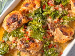 crockpot chicken thighs in a white baking dish with creamy coconut lemon sauce and kale