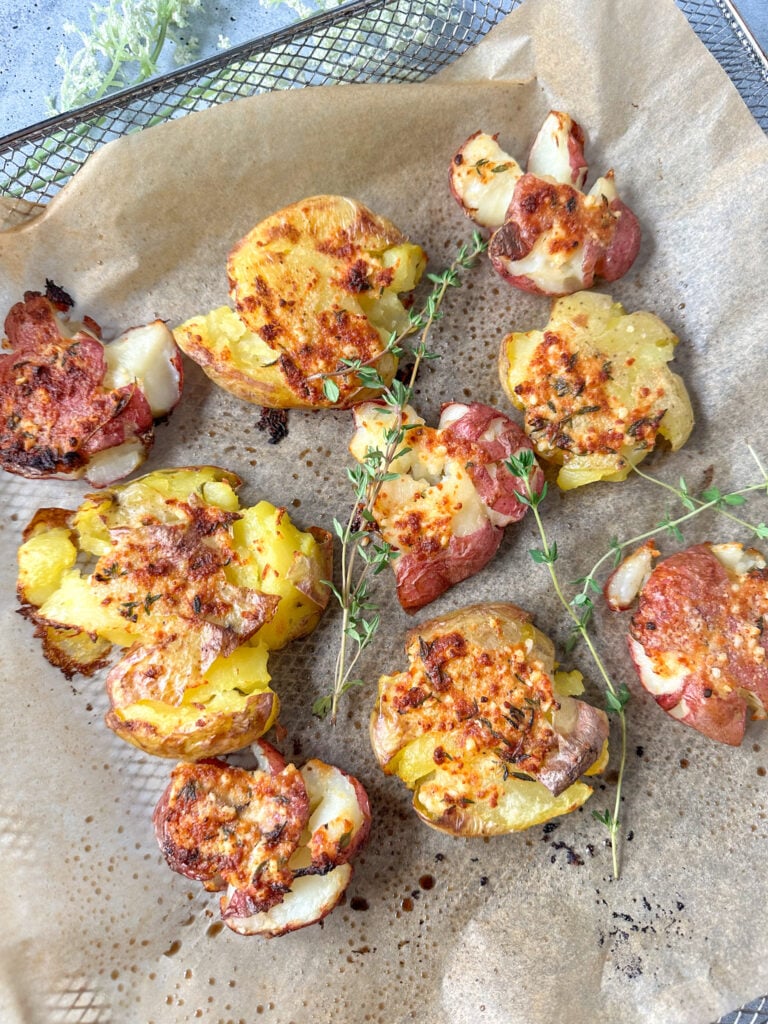 crispy air fryer smashed potatoes garnished with fresh thyme leaves