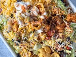 Fritos topped with ground beef, shredded cheese, lettuce, black olives, salsa, and sour cream