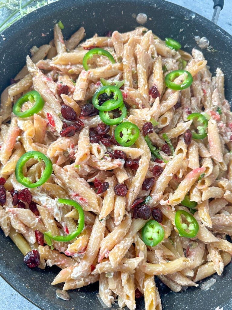 Creamy cranberry and jalapeño penne pasta in a black skillet