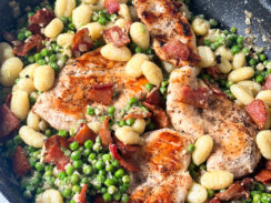 pan seared chicken in a black skillet with peas, bacon, and gnocchi