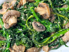 sautéed broccoli rabe with mushrooms, garlic, and grated parmesan cheese on a white serving dish