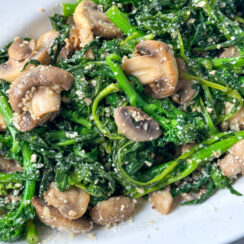 sautéed broccoli rabe with mushrooms, garlic, and grated parmesan cheese on a white serving dish