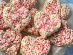 heart shaped Rice Krispie treats with pink sprinkles on a plate with parchment paper