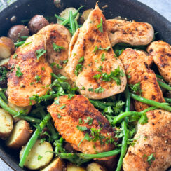 pan seared chicken in a black skillet with baby potatoes and green beans