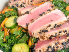 perfectly sesame seared ahi tuna slices on a bed of kale with cucumbers, shredded carrots, and sesame dressings