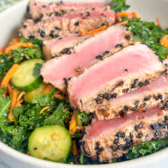 perfectly sesame seared ahi tuna slices on a bed of kale with cucumbers, shredded carrots, and sesame dressings