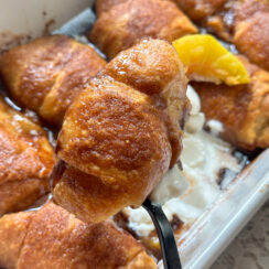 peach dumplings made with crescent rolls in a white baking dish with cinnamon sugar topping, vanilla ice cream and peach slice