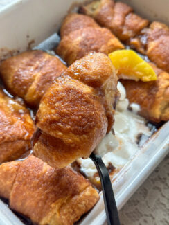 peach dumplings made with crescent rolls in a white baking dish with cinnamon sugar topping, vanilla ice cream and peach slice