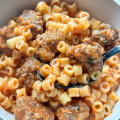 homemade spaghettiOs with mini meatballs in a gray bowl with black spoon