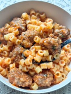 homemade spaghettiOs with mini meatballs in a gray bowl with black spoon