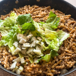 Big Mac cheeseburger pasta in a black skillet topped white shredded lettuce and pickles easy one pan meal