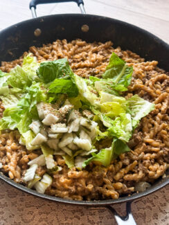 Big Mac cheeseburger pasta in a black skillet topped white shredded lettuce and pickles easy one pan meal