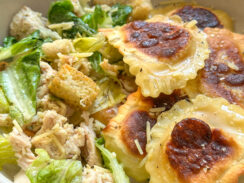 pan toasted lemon ravioli in a white bowl with creamy chicken caesar salad