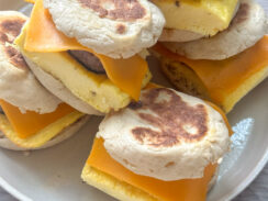 ready to freeze English muffin breakfast sandwiches stacked on a white plate