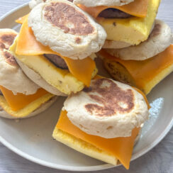 ready to freeze English muffin breakfast sandwiches stacked on a white plate