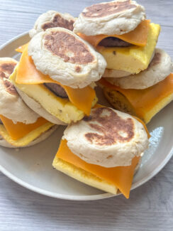 ready to freeze English muffin breakfast sandwiches stacked on a white plate