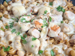 one pan french onion chicken pasta in a black skillet smothered in swiss cheese and freshly diced parsley leaves