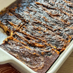 ricotta pumpkin pie brownies in a white baking dish with a slice missing