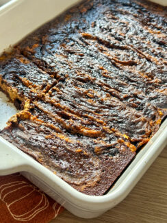 ricotta pumpkin pie brownies in a white baking dish with a slice missing