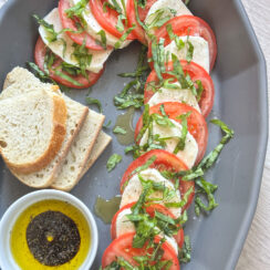 candy cane caprese made with layers of fresh mozzarella, tomatoes, shredded basil, and served with crusty bread and balsamic glaze.