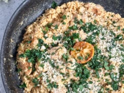 delicious one pan dinner creamy chicken caesar risotto in a black skillet with a lemon, parsley and parmesan cheese sprinkled on top