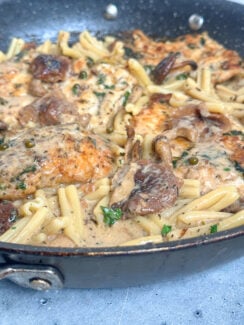 creamy chicken marsala with fresh peppercorns, the juiciest chicken, pasta, shiitake mushrooms in a black skillet