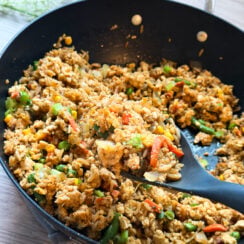 perfectly toasted garlic-ranch chicken fried rice in a black skillet with a gray serving spoon loaded with protein and family-approved for an easy recipe that everyone will love