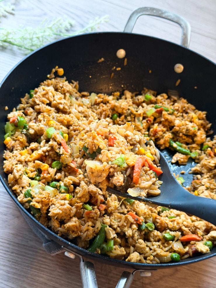 perfectly toasted garlic-ranch chicken fried rice in a black skillet with a gray serving spoon loaded with protein and family-approved for an easy recipe that everyone will love