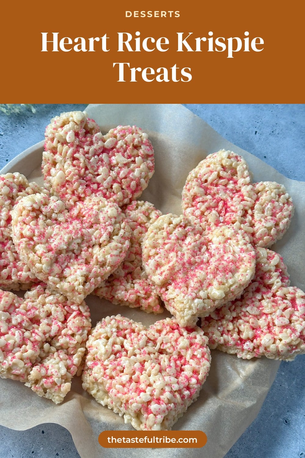 heart shaped Rice Krispie treats with pink sprinkles on a plate with parchment paper