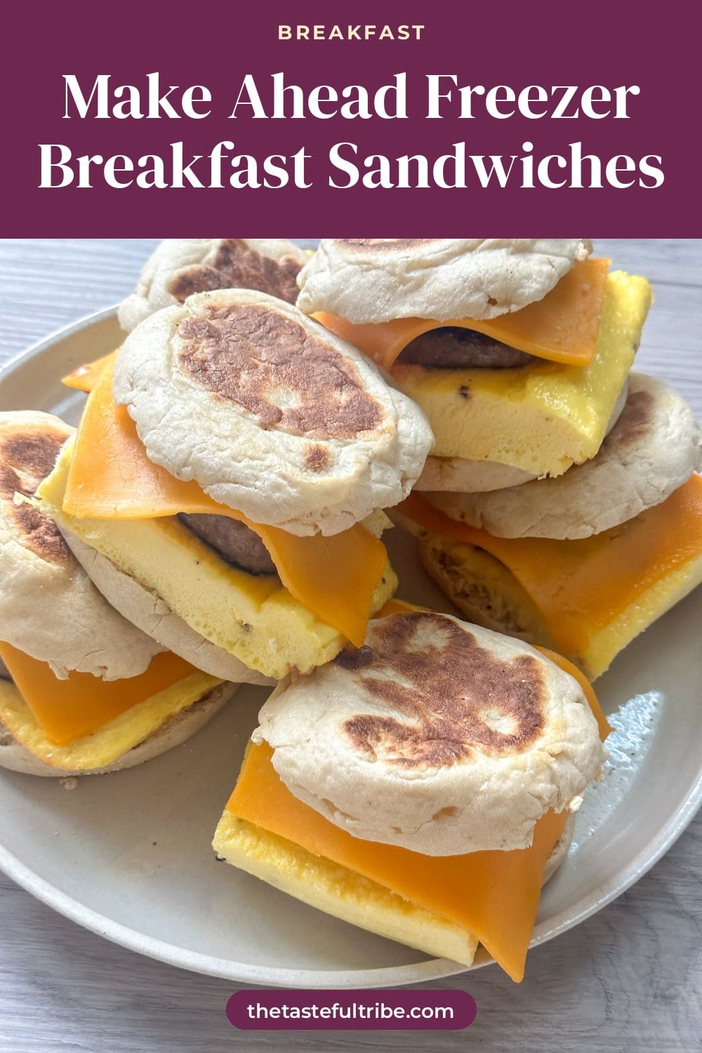 ready to freeze English muffin breakfast sandwiches stacked on a white plate
